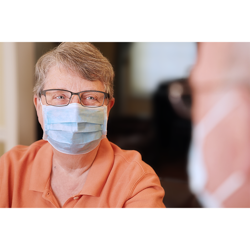 Almine 3-Ply Face Mask One Size 10ct Light Blue worn by elderly person with glasses indoors.