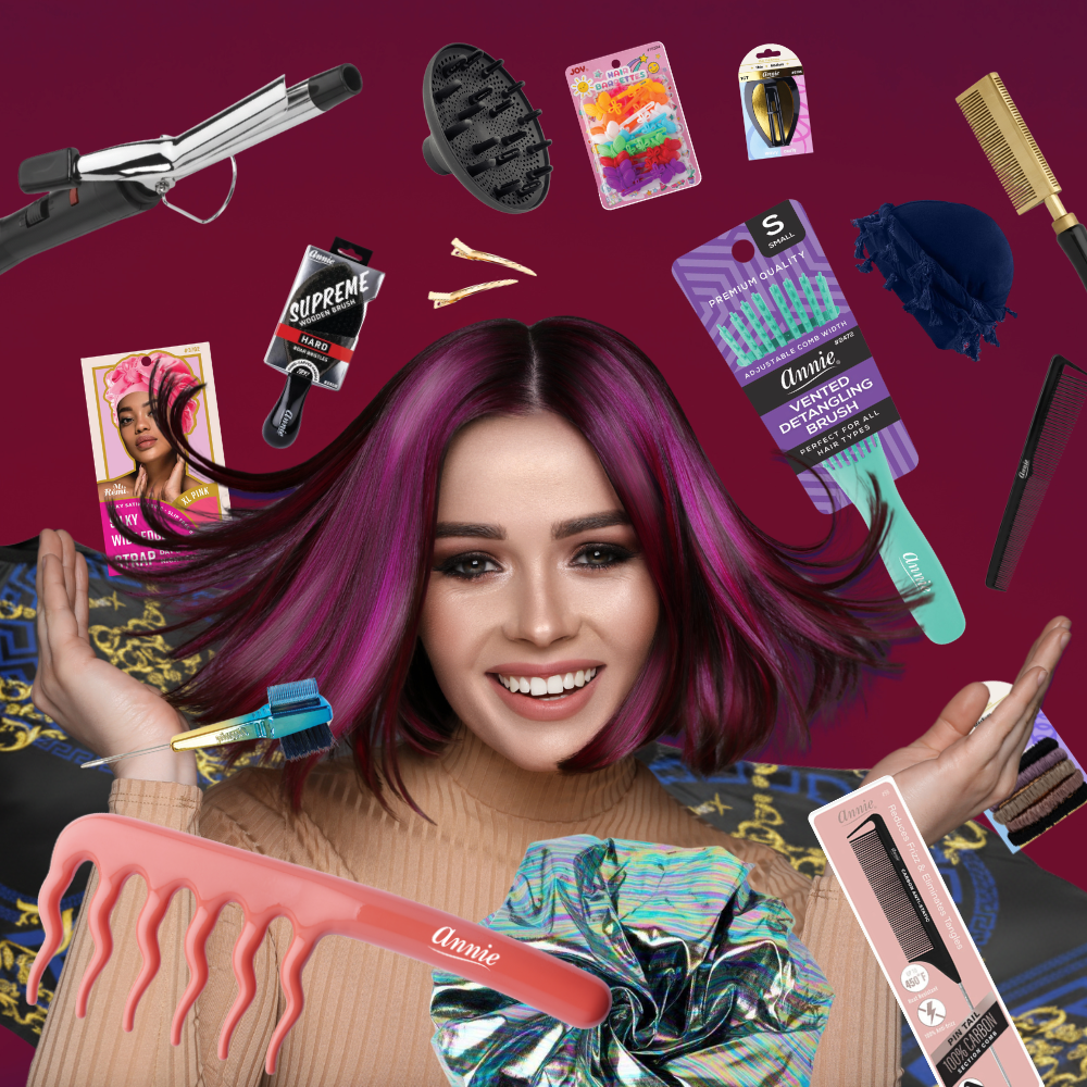 A smiling woman with vibrant purple and magenta hair surrounded by various hair care tools and accessories including combs, clips, a curling iron, a hair bonnet, and brushes against a deep magenta background.