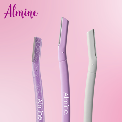 Three Almine precision facial dermaplaners in glittery purple, solid lavender, and matte white on pink background