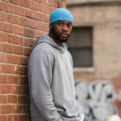 A man wearing Mr. Durag Spandex Dome Cap, 1 Count, Assorted Colors in bright blue, standing against a brick wall outdoors, featuring smooth, breathable spandex for comfortable wave training.