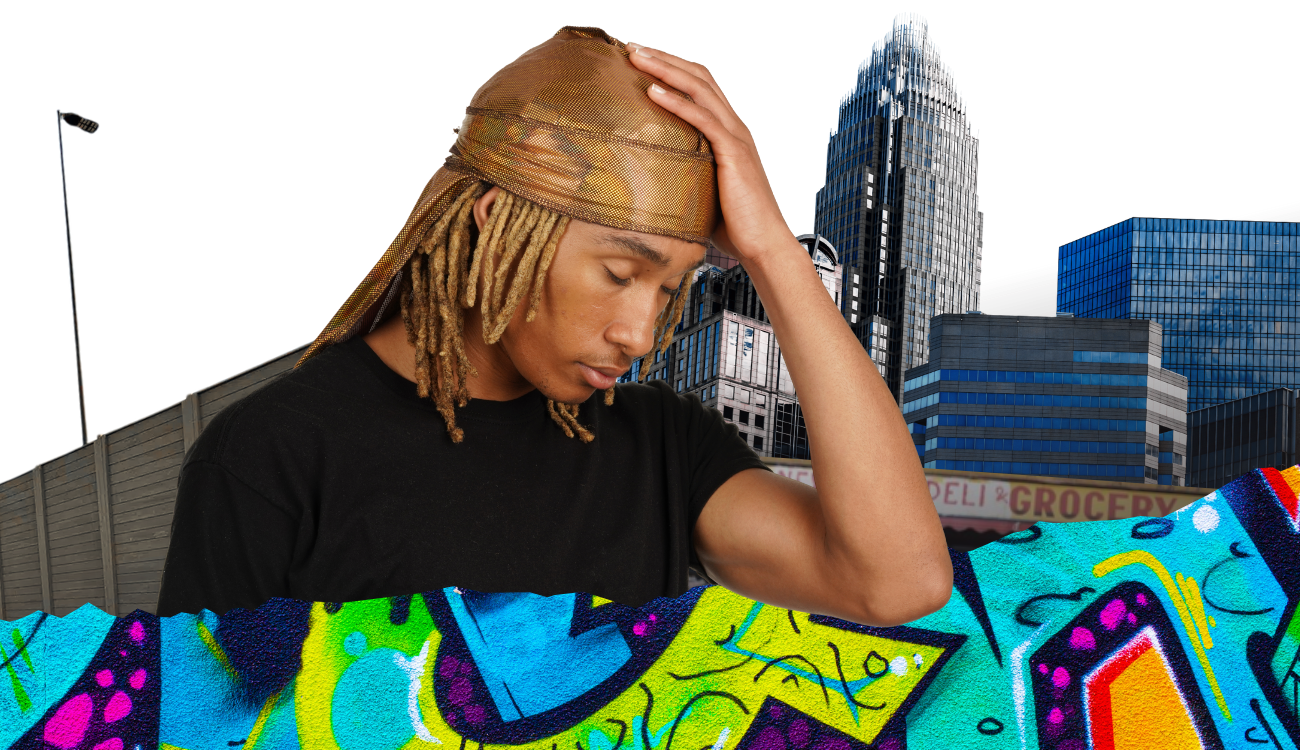 Young man with dreadlocks wearing a brown durag and black t-shirt standing in front of city buildings and colorful graffiti wall