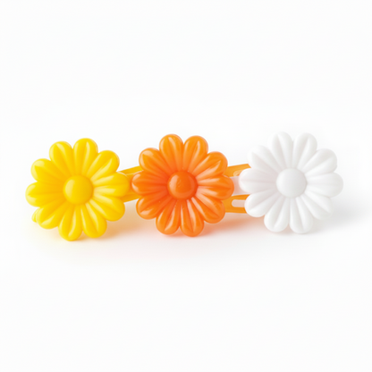 Close-up of three daisy-shaped barrettes in bright yellow, vibrant orange, and white, designed for secure, snag-free hold on textured and multicultural hair.