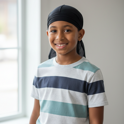 Young boy wearing a black Annie Kids' durag made of synthetic fabric, smiling indoors with natural light, demonstrating a comfortable fit for textured hair care.