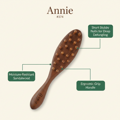 Oval paddle brush made of moisture-resistant sandalwood with short stubby nubs for deep detangling and an ergonomic grip handle, designed for textured hair.