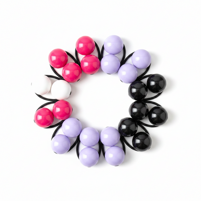 Assorted colorful twin bead ponytail holders arranged in a circle, designed for firm, snag-free hold on textured and multicultural hair by Annie International.