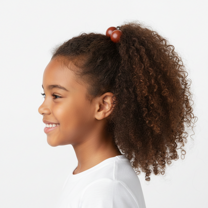 Young girl with textured natural hair styled in a ponytail secured by twin bead ponytailers in warm earth tones, showcasing a firm, snag-free hold designed for multicultural hair.