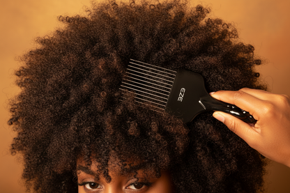 Hand using EZE Urban Series Fist Styling Pik Short 2.5 Inch, 1 Count, Black to detangle and style tightly coiled natural hair against warm background.