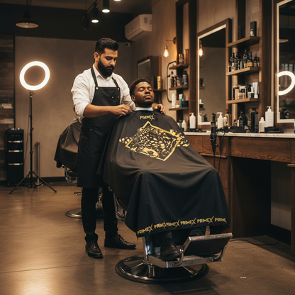 Barber draping client with PrimeX Premium Professional Barber Cape, 1 Count, Jaguar featuring a bold golden jaguar face design and branded trim in a modern barbershop setting.