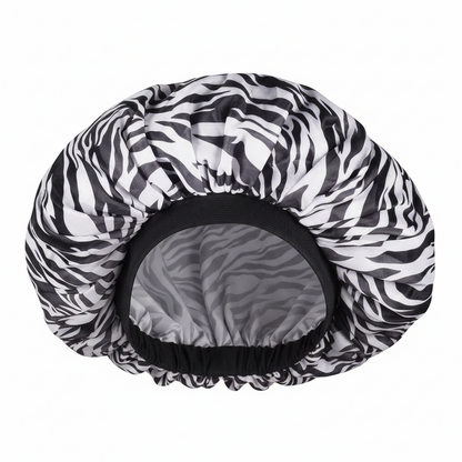 Extra-large satin bonnet with a black and white zebra pattern and a smooth black elastic band, designed to protect textured and natural hair during day and night use.